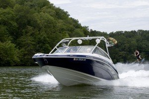 man wakeboarding behind a blue and white ski boat