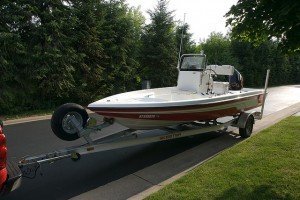 red and white fishing boat on trailer behind truck