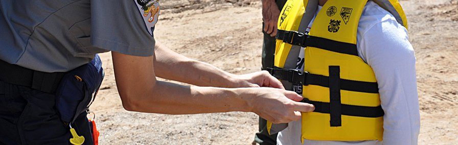 person adjusting life jacket straps on a child