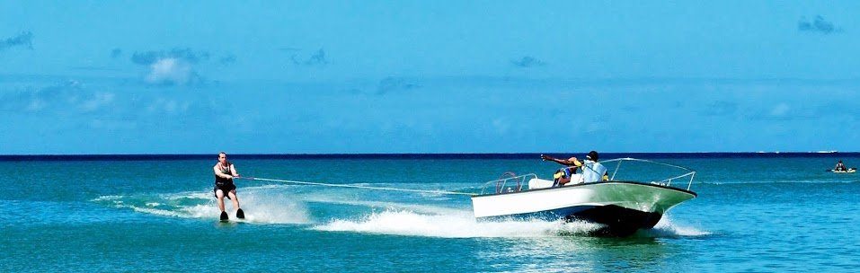 man water skiing behind a boat on a sunny day
